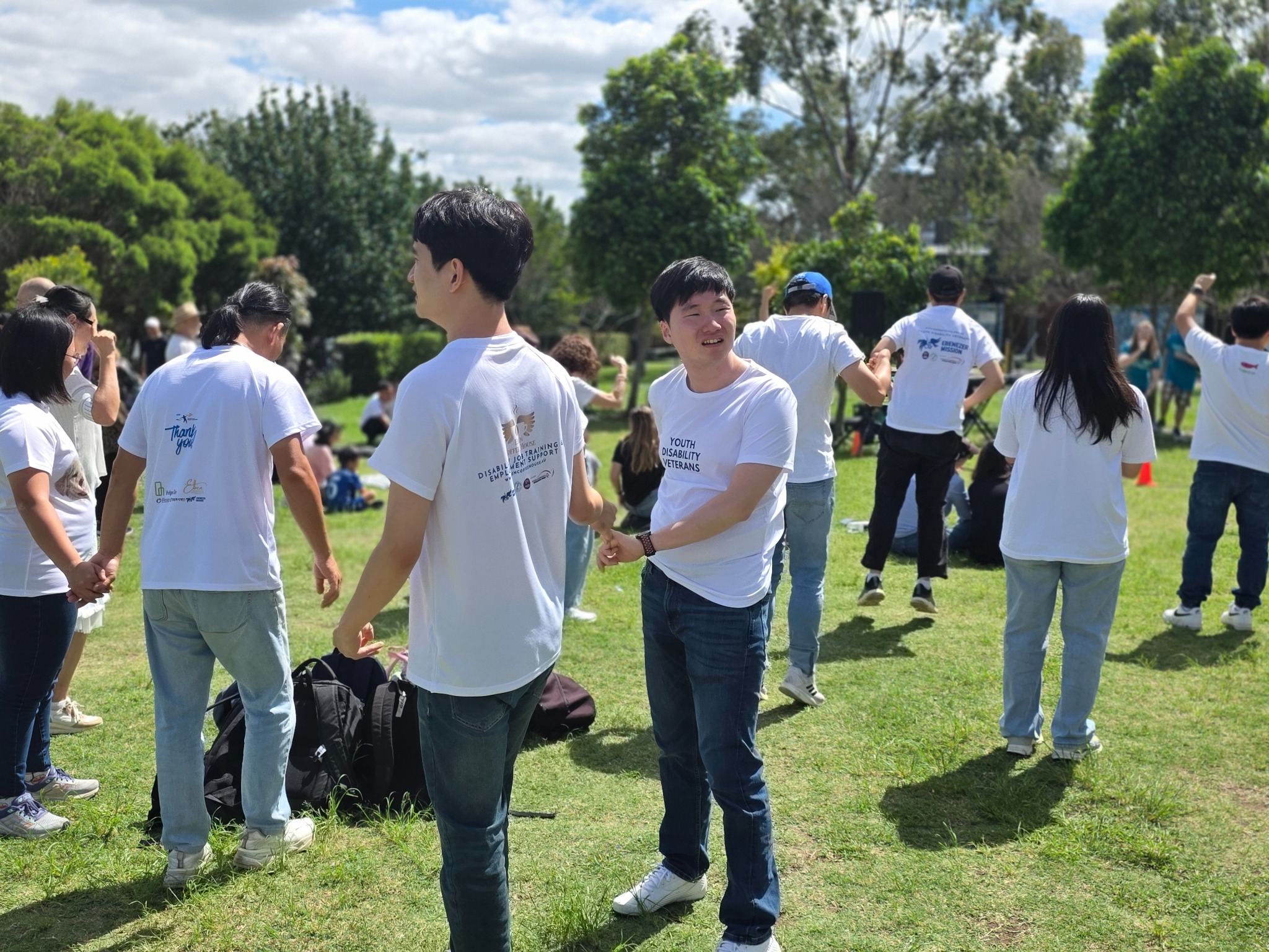 Participants and supporters enjoying a group activity together outdoors in a park
