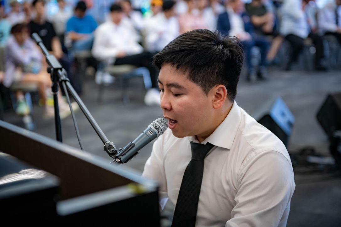 Jonathan Yang singing into a microphone while performing at the piano